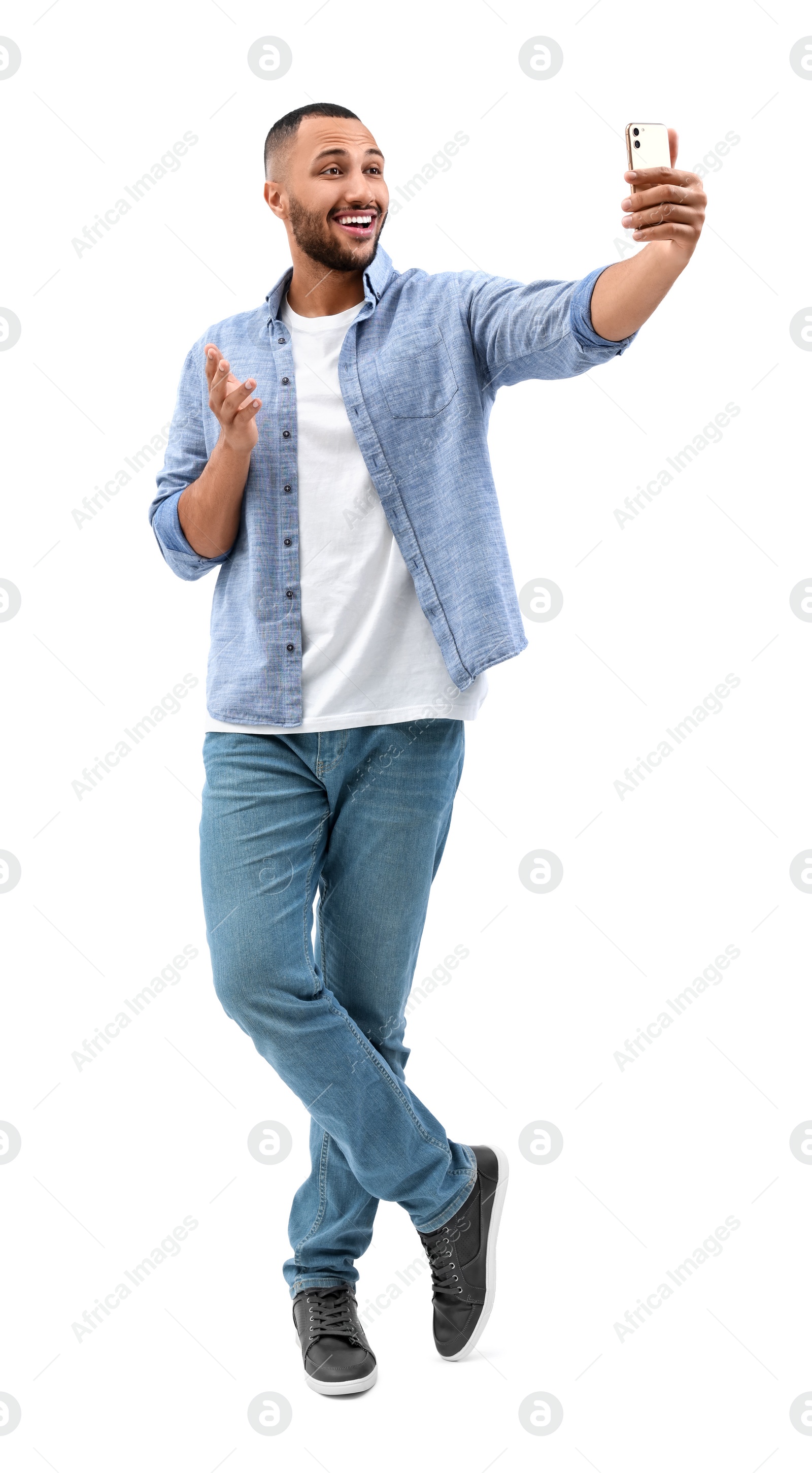 Photo of Smiling young man taking selfie with smartphone on white background