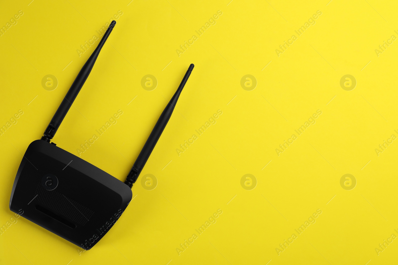 Photo of Modern Wi-Fi router on yellow background, top view. Space for text