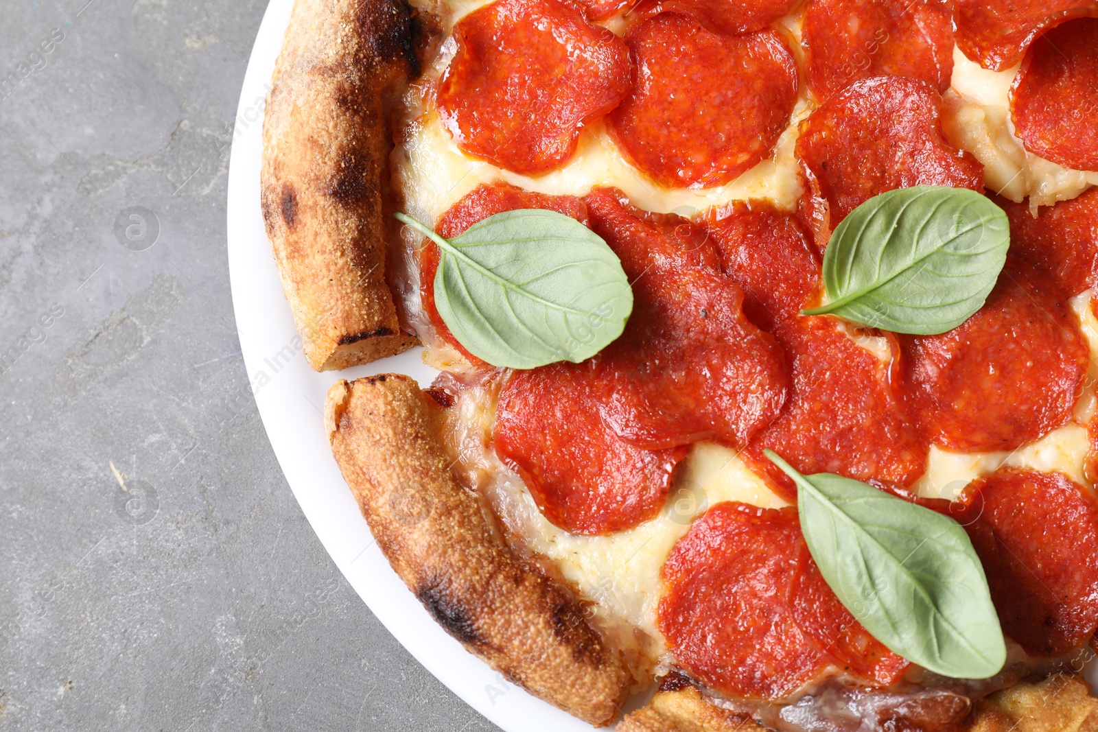 Photo of Tasty pepperoni pizza with basil on grey table, top view