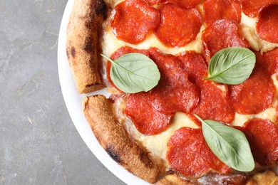 Tasty pepperoni pizza with basil on grey table, top view