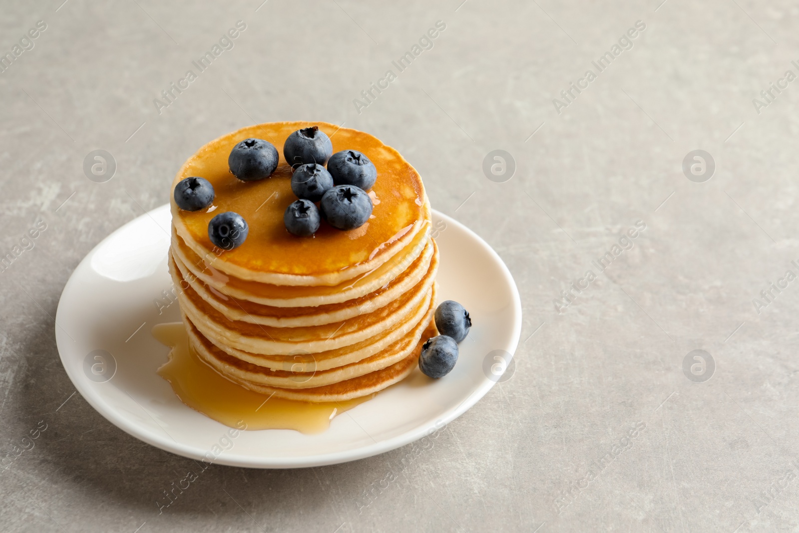 Photo of Plate with pancakes and berries on grey background