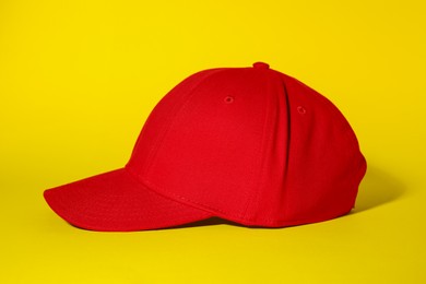 Photo of Stylish red baseball cap on yellow background