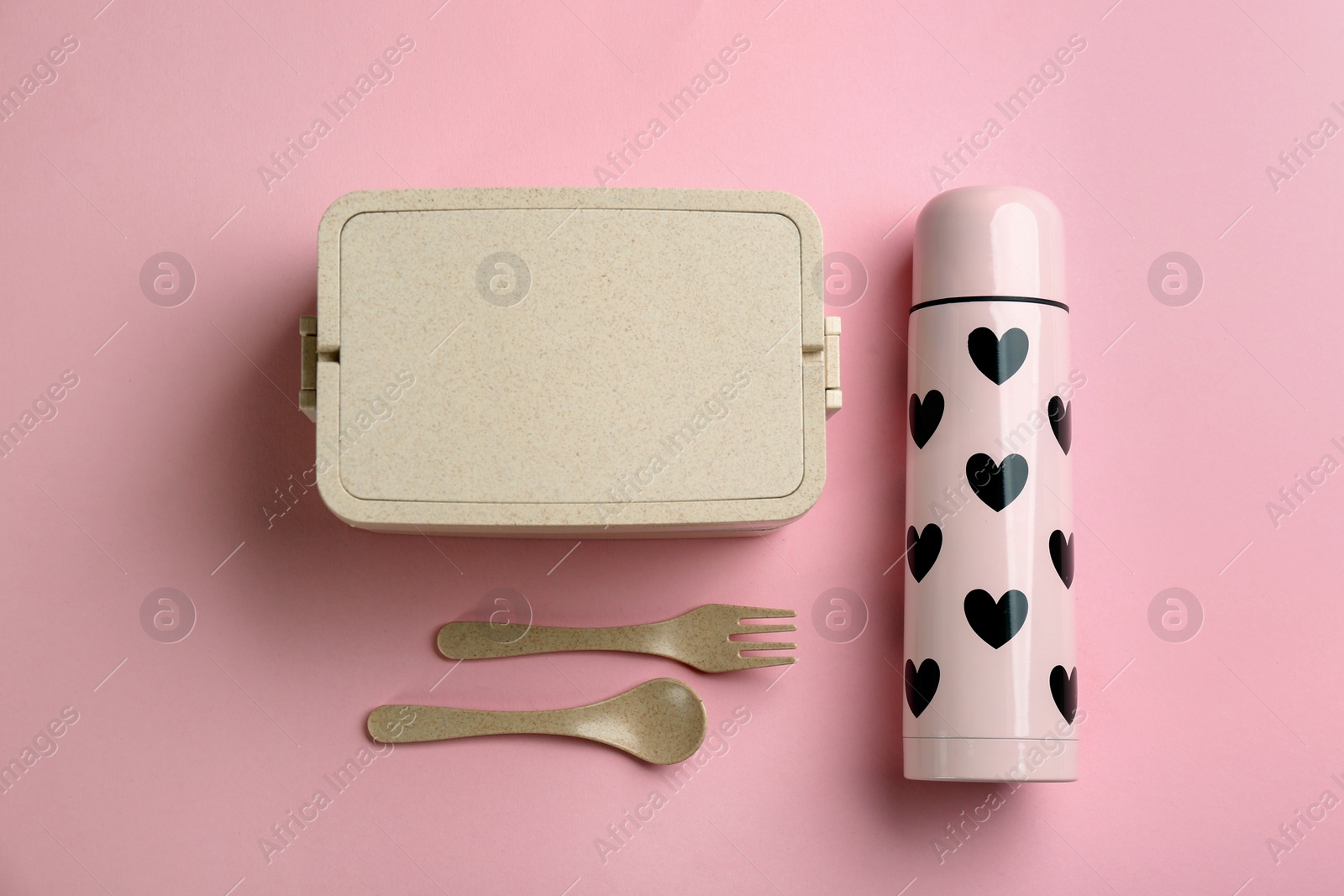 Photo of Thermos and lunch box with cutlery on pink background, flat lay