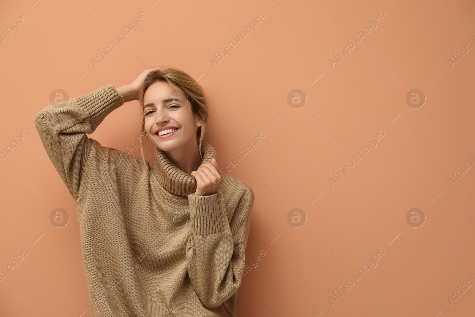 Photo of Beautiful young woman wearing knitted sweater on light brown background. Space for text