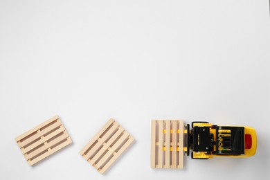 Toy forklift and wooden pallets on white background, top view