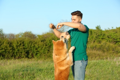 Photo of Young man playing with adorable Akita Inu dog in park