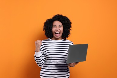 Photo of Emotional young woman with laptop on orange background