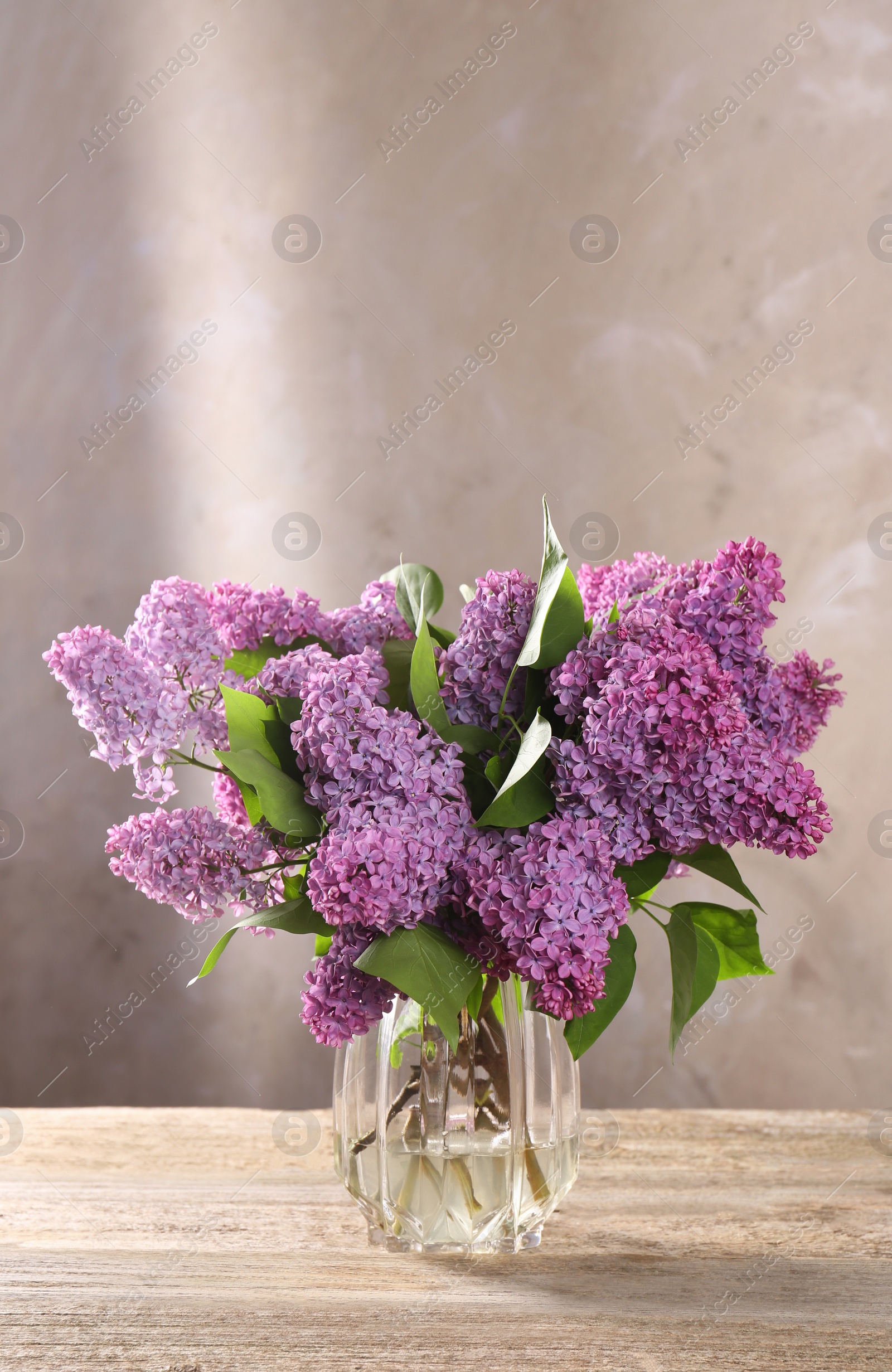 Photo of Beautiful lilac flowers in vase on wooden table