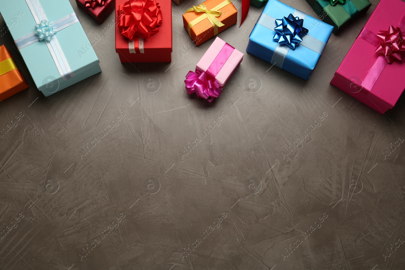 Photo of Many colorful gift boxes on grey table, above view. Space for text