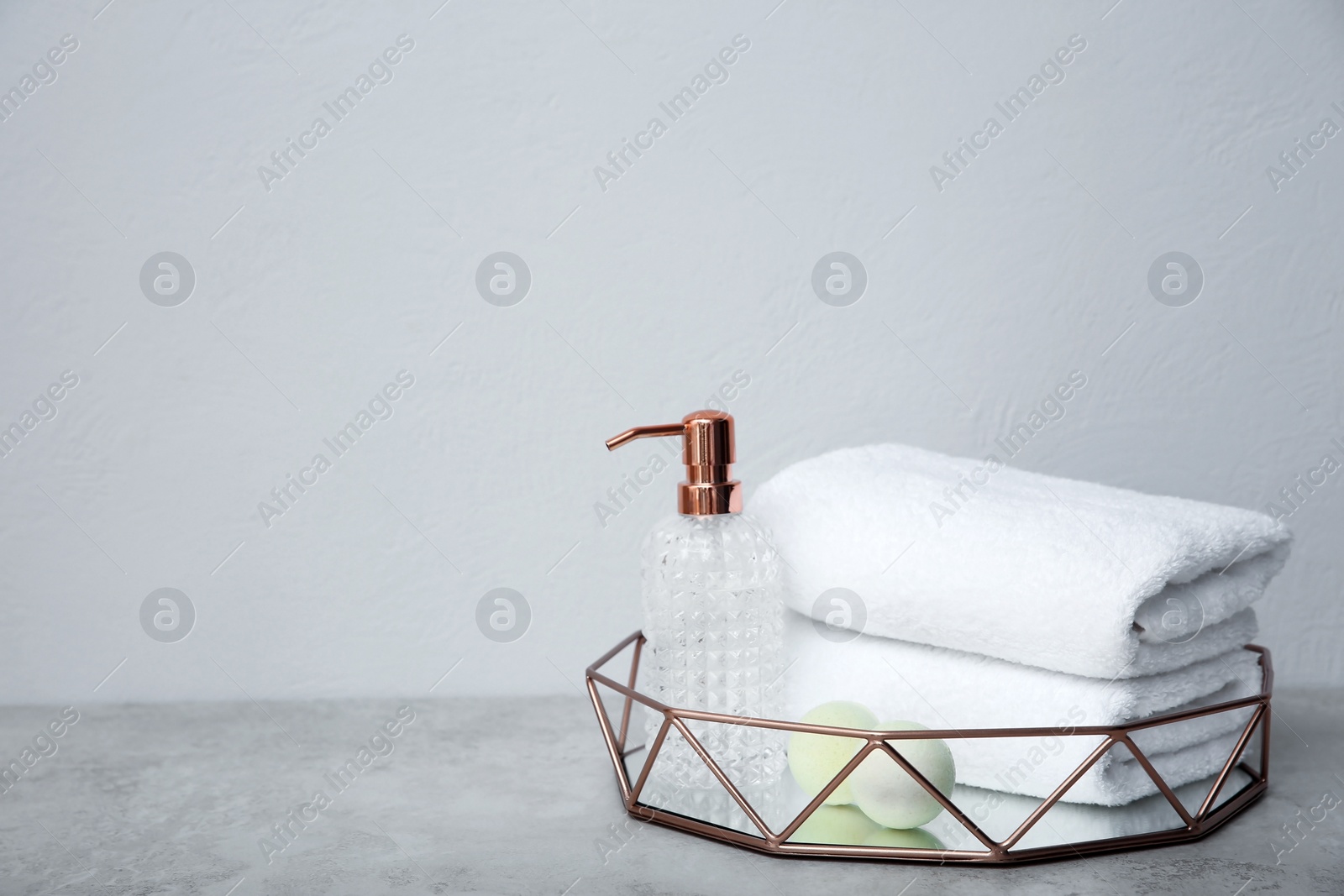 Photo of Tray with towels and toiletries on table against grey background