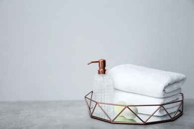 Tray with towels and toiletries on table against grey background