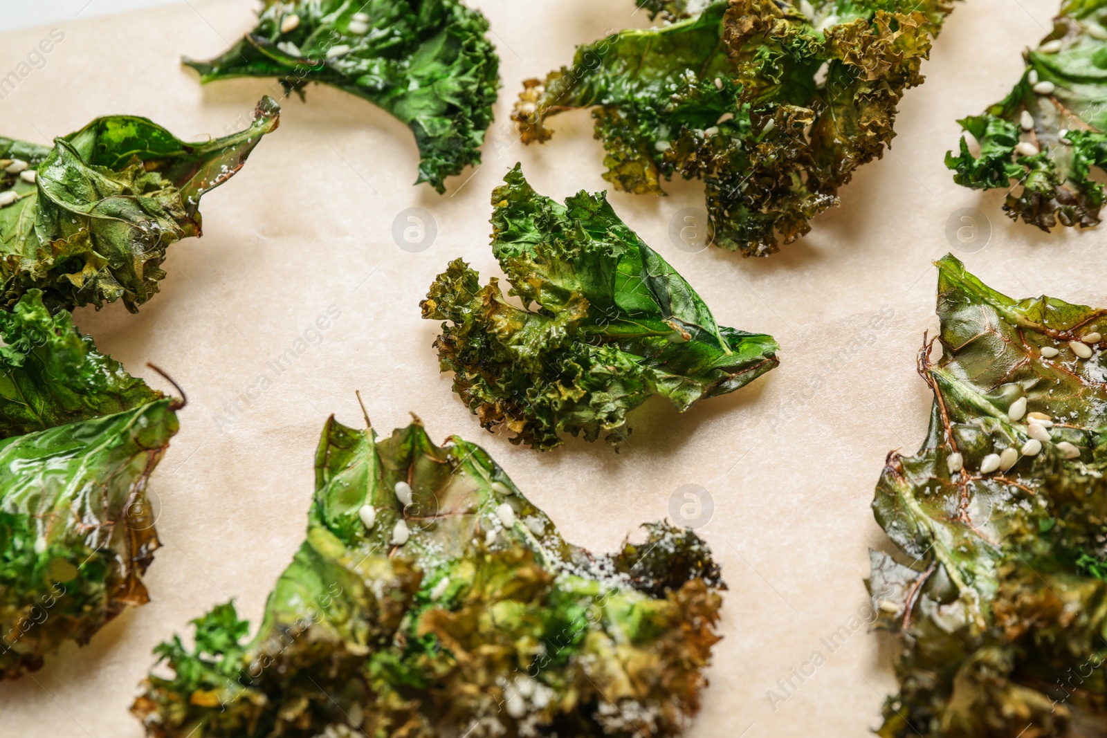 Photo of Tasty baked kale chips on light table, closeup