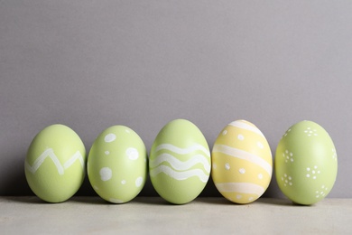 Painted Easter eggs on table against color background, space for text