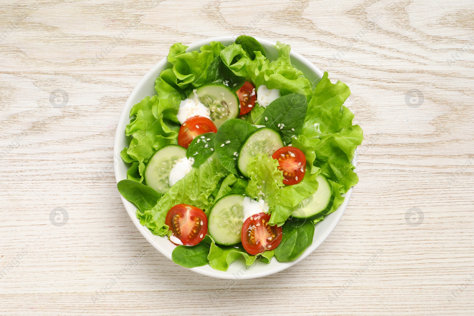 Photo of Delicious salad in bowl on white wooden table, top view