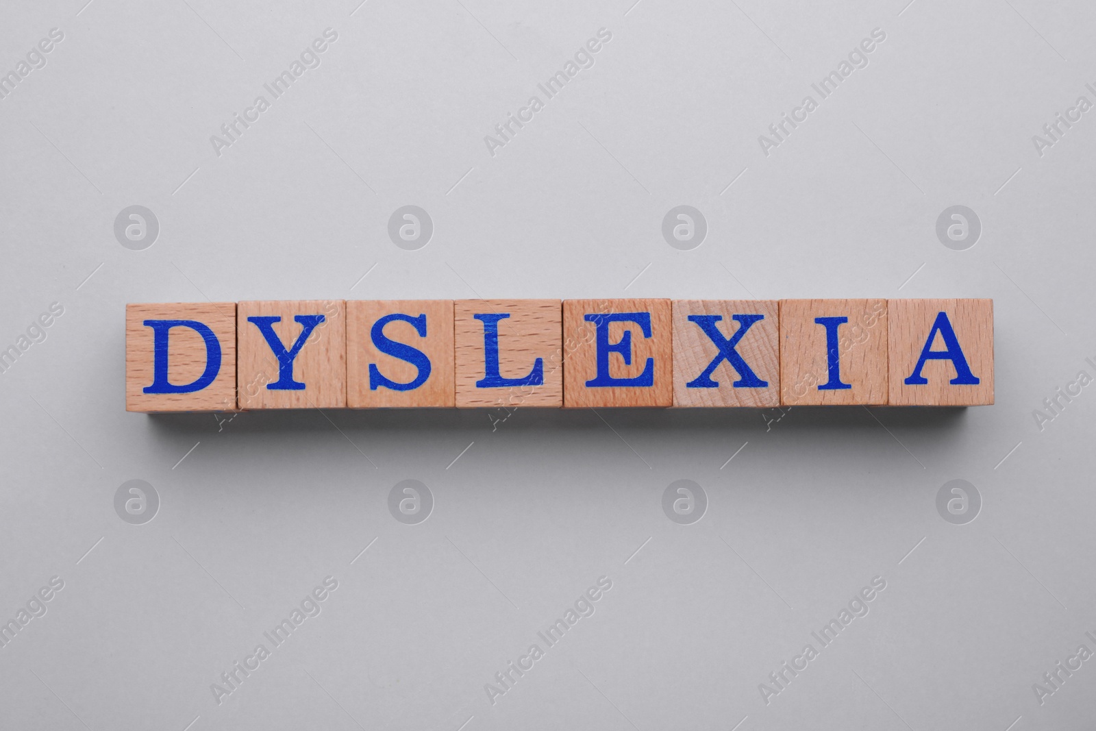 Photo of Wooden cubes with word Dyslexia on light grey background, flat lay