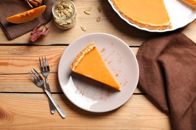 Flat lay composition with piece of fresh delicious homemade pumpkin pie on wooden background