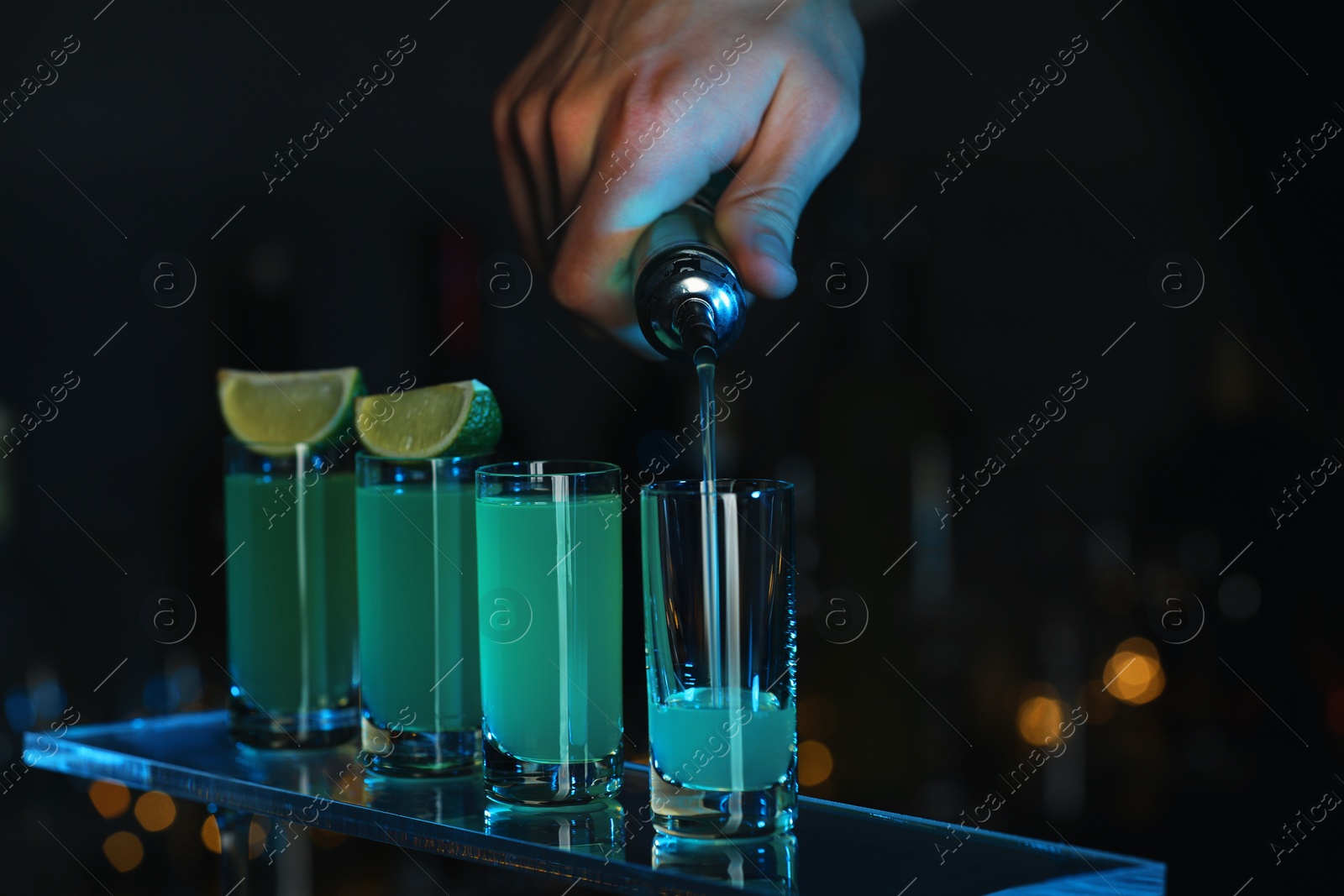 Photo of Bartender pouring alcohol drink into shot glass on blurred background, closeup. Space for text