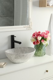 Vase with beautiful pink tulips near sink in bathroom