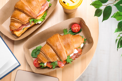Tasty croissant sandwiches on wooden table, flat lay