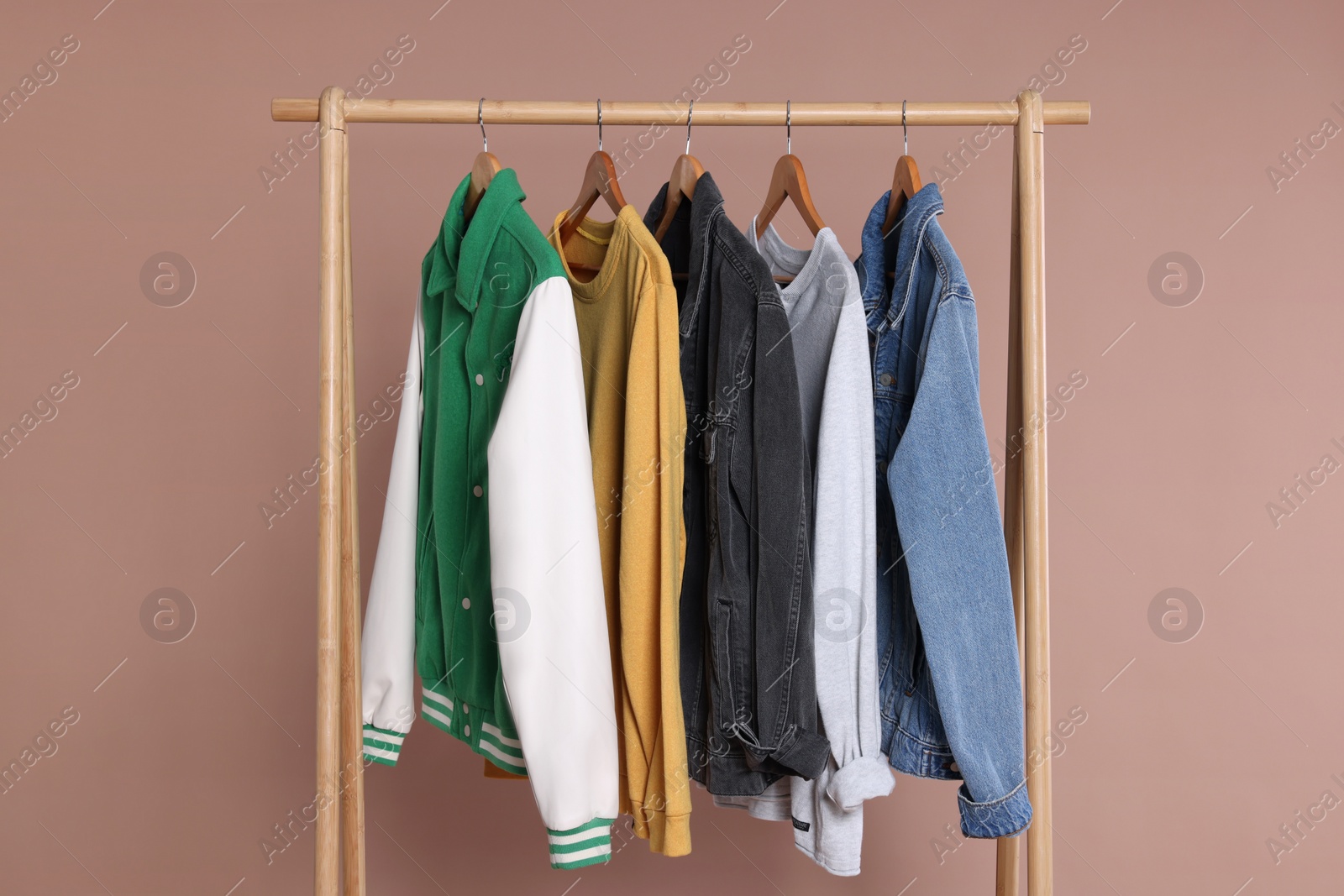 Photo of Rack with stylish clothes on wooden hangers against beige background