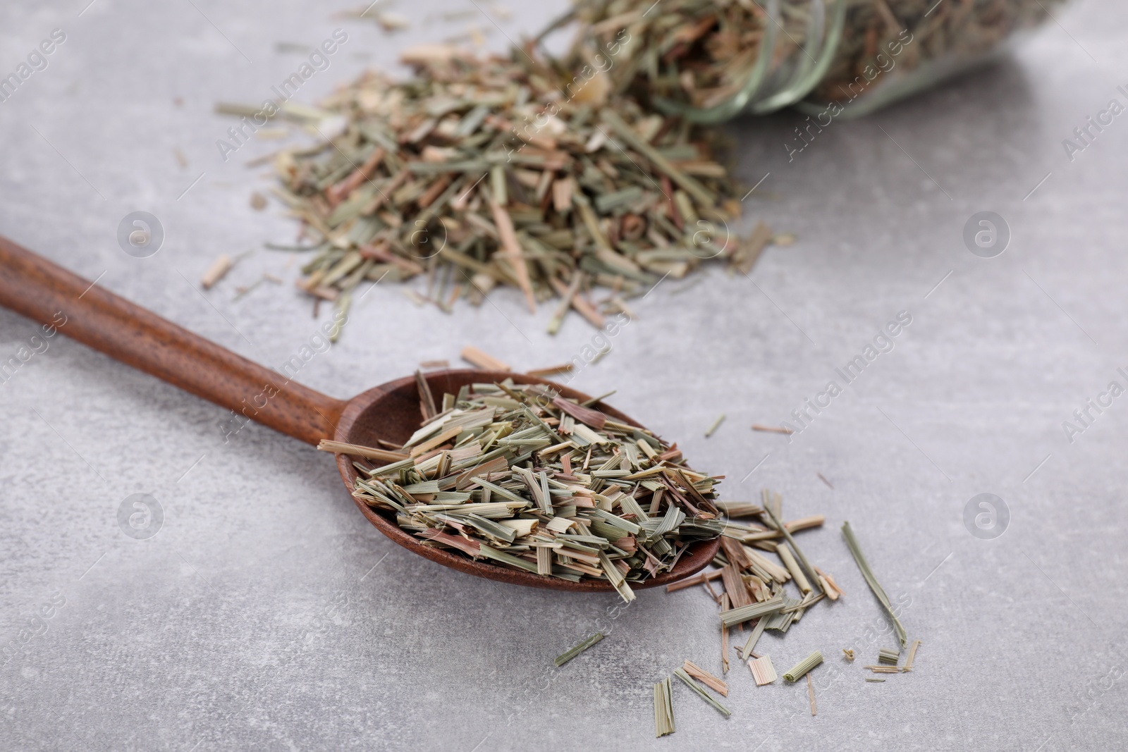 Photo of Wooden spoon with aromatic dried lemongrass on light grey table