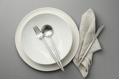 Photo of Clean dishes and cutlery on grey background, top view