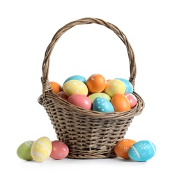 Wicker basket with painted Easter eggs on white background