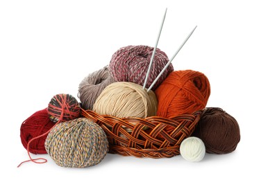 Photo of Wicker basket with different balls of woolen knitting yarns and needles on white background