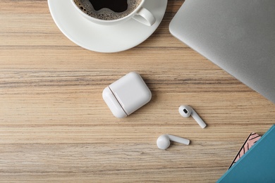 Photo of Flat lay composition with wireless earphones and laptop on wooden table