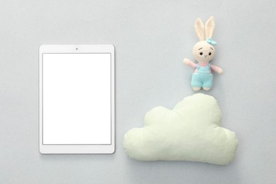 Photo of Modern tablet, toy cloud and bunny on light background, flat lay. Space for text