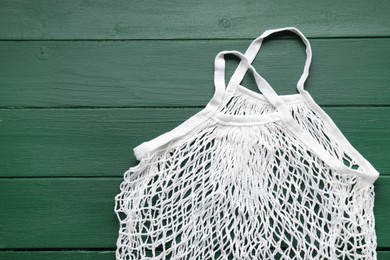 Photo of White string bag on green wooden table, top view