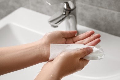 Photo of Woman wiping hands with paper towel in bathroom, closeup