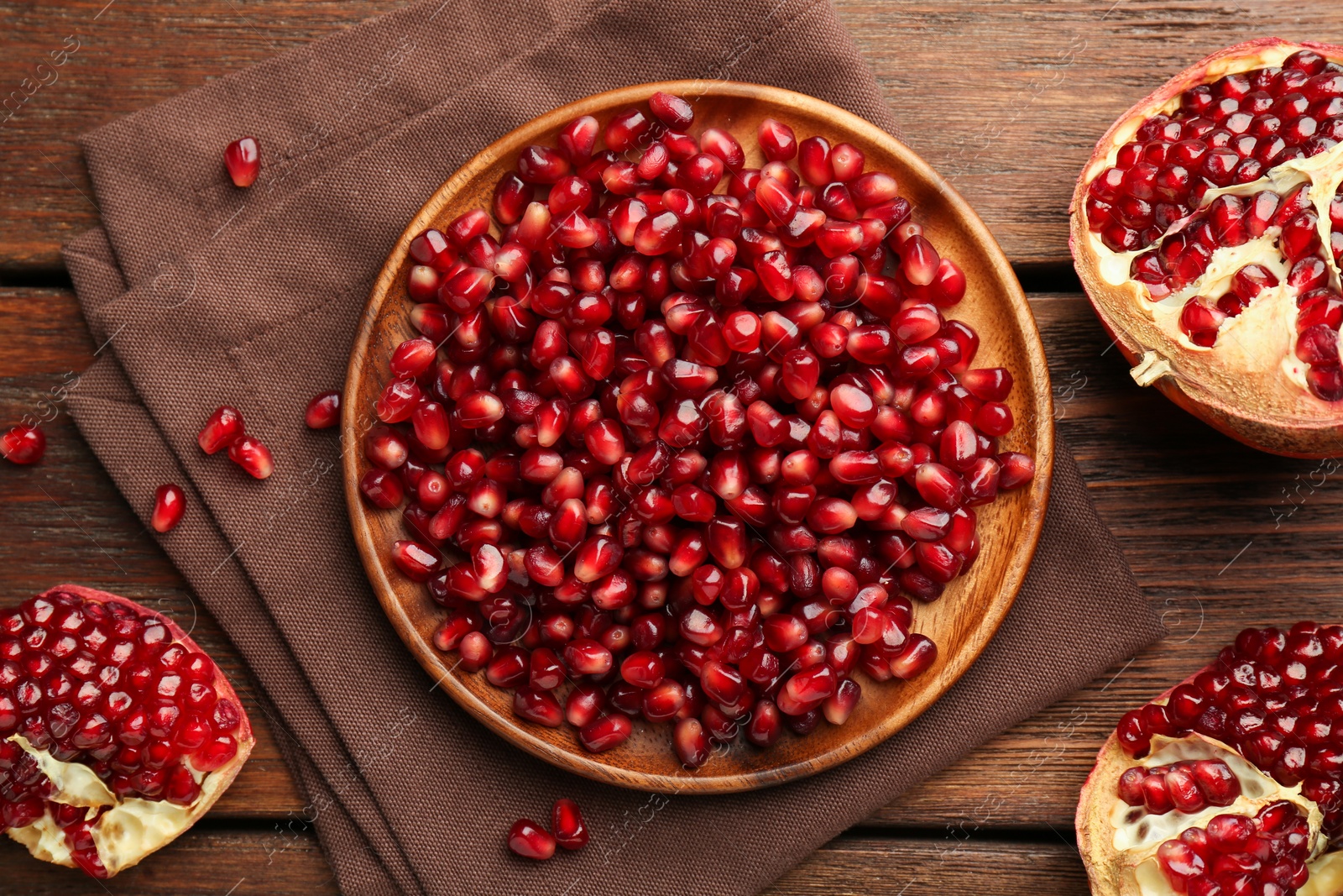 Photo of Ripe juicy pomegranates and grains on wooden table, flat lay