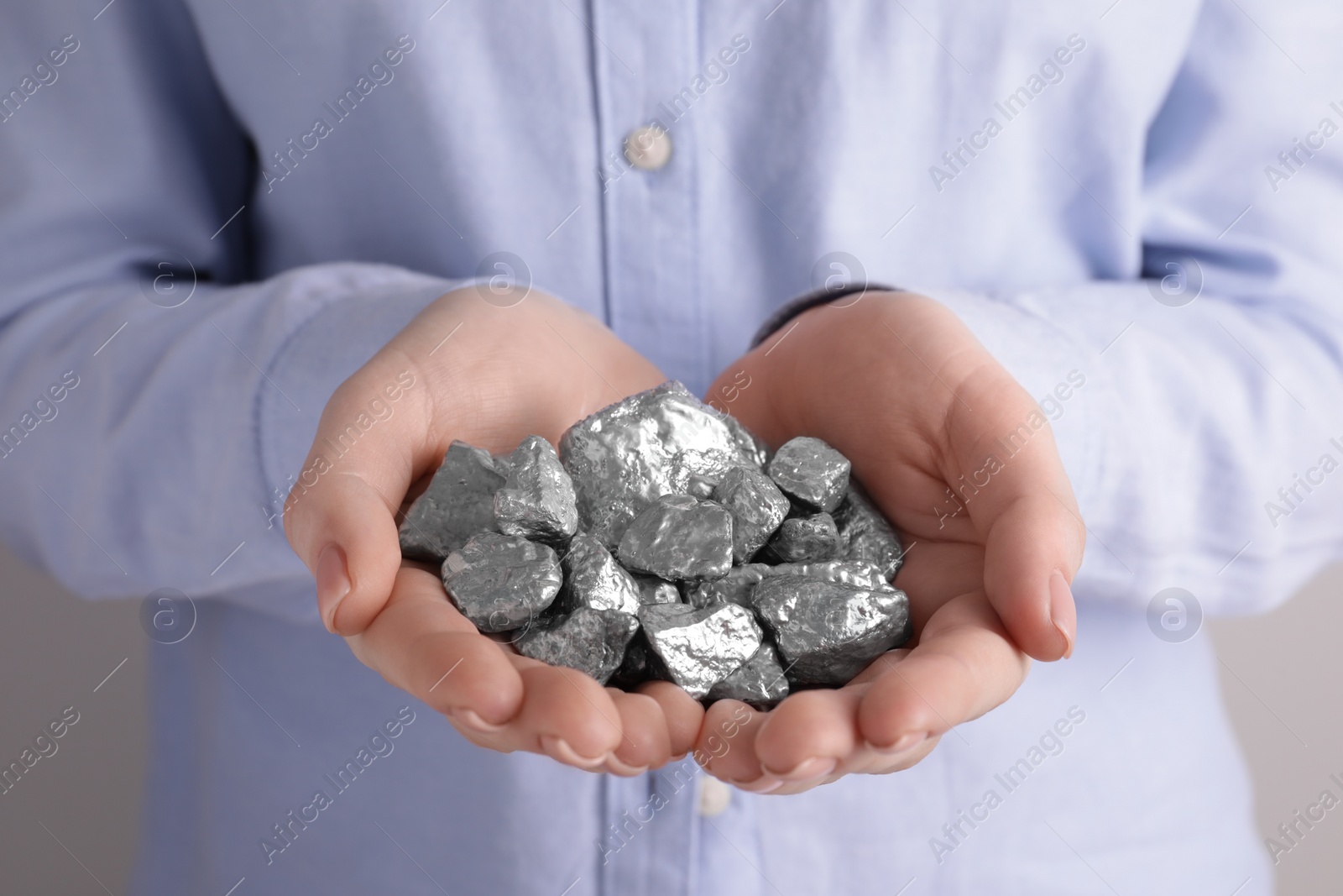 Photo of Woman with silver nuggets on light grey background, closeup