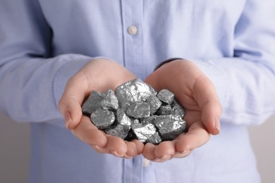 Woman with silver nuggets on light grey background, closeup