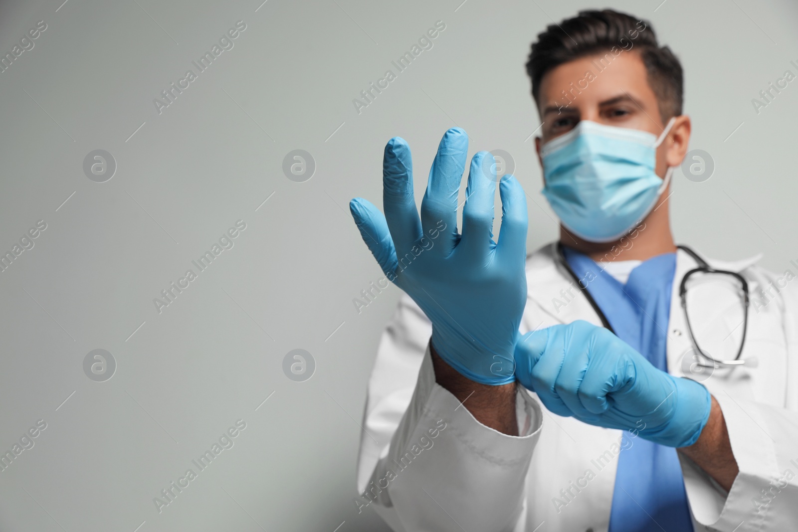 Photo of Doctor in protective mask and medical gloves against light grey background, focus on hands. Space for text