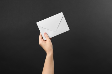 Photo of Woman holding white paper envelope on black background, closeup