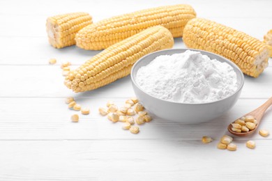 Photo of Bowl of corn starch, ripe cobs and kernels on white wooden table. Space for text