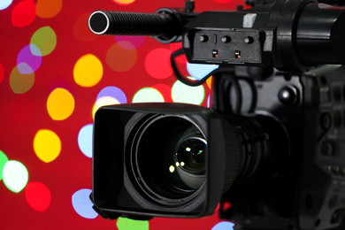 Modern video camera against blurred colorful lights, closeup