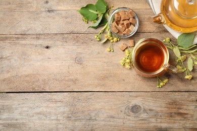 Photo of Flat lay composition with tasty tea and linden blossom on wooden table. Space for text