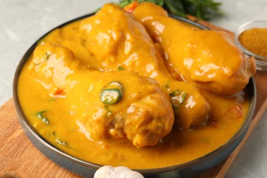 Photo of Tasty chicken curry, garlic and spice on grey textured table, closeup