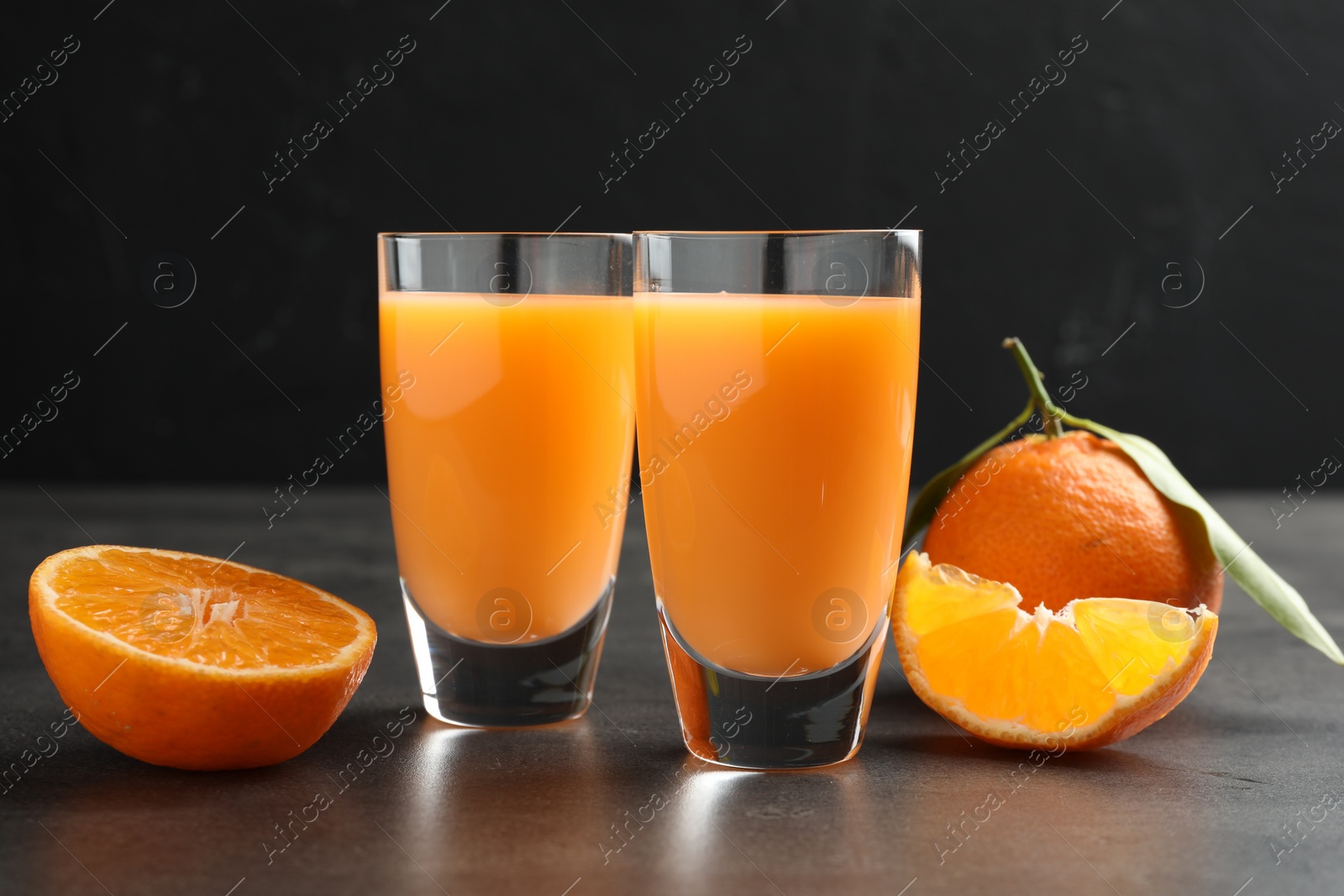 Photo of Delicious tangerine liqueur and fresh fruits on grey table