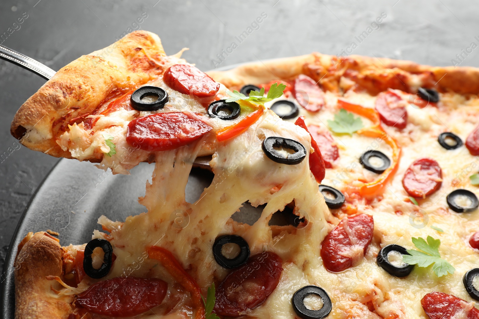 Photo of Taking piece of tasty pizza at table, closeup