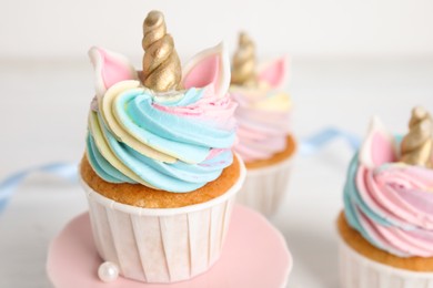 Photo of Plate with cute sweet unicorn cupcake on table, closeup