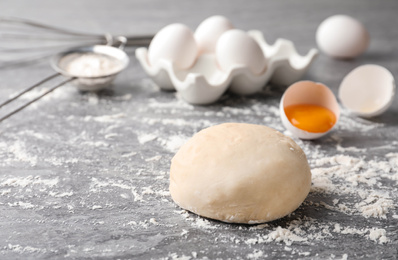 Photo of Wheat dough and products on grey table, space for text. Cooking pastries