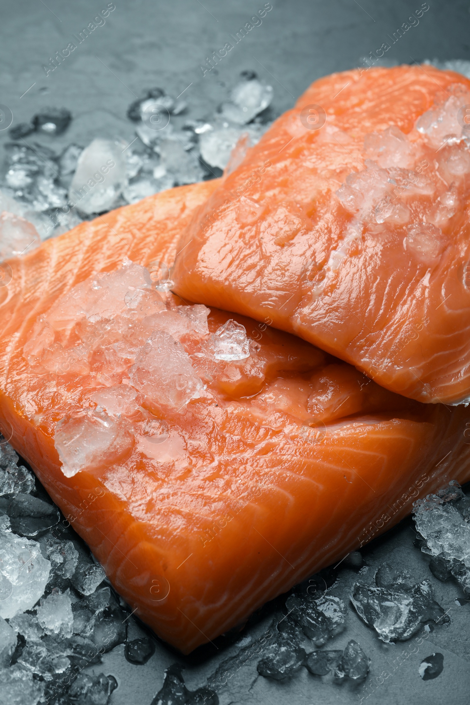 Photo of Fresh raw salmon with ice on black table, closeup