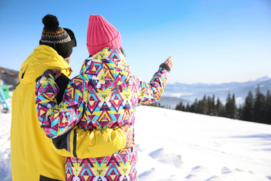 Photo of Young couple at ski resort, space for text. Winter vacation