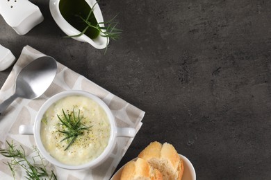 Photo of Delicious cream soup with tarragon, spices and potato in bowl served on dark textured table, flat lay. Space for text