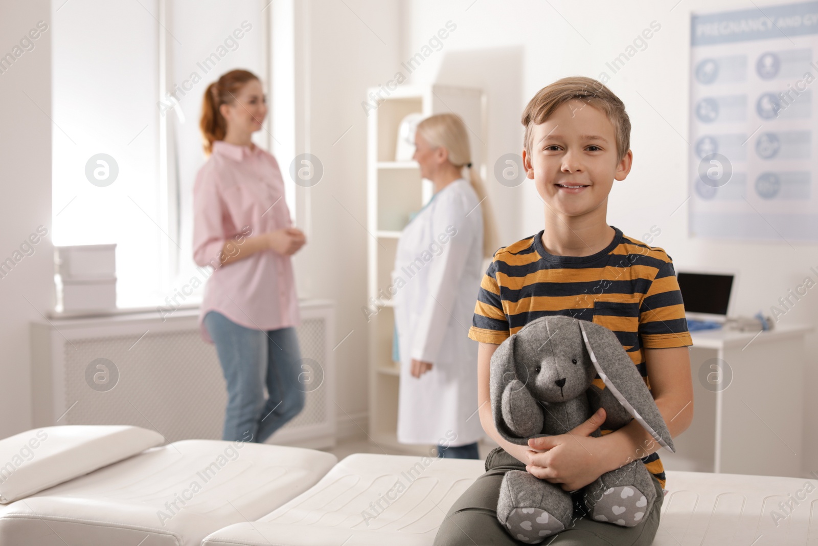 Photo of Adorable child with toy and mother visiting doctor at hospital