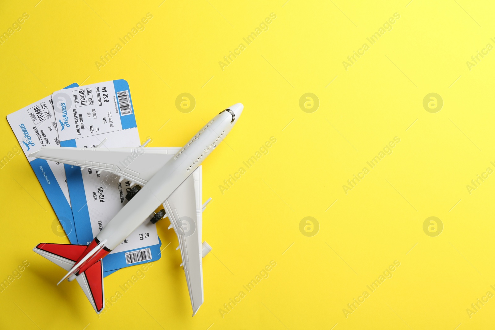 Photo of Toy airplane and tickets on yellow background, flat lay. Space for text